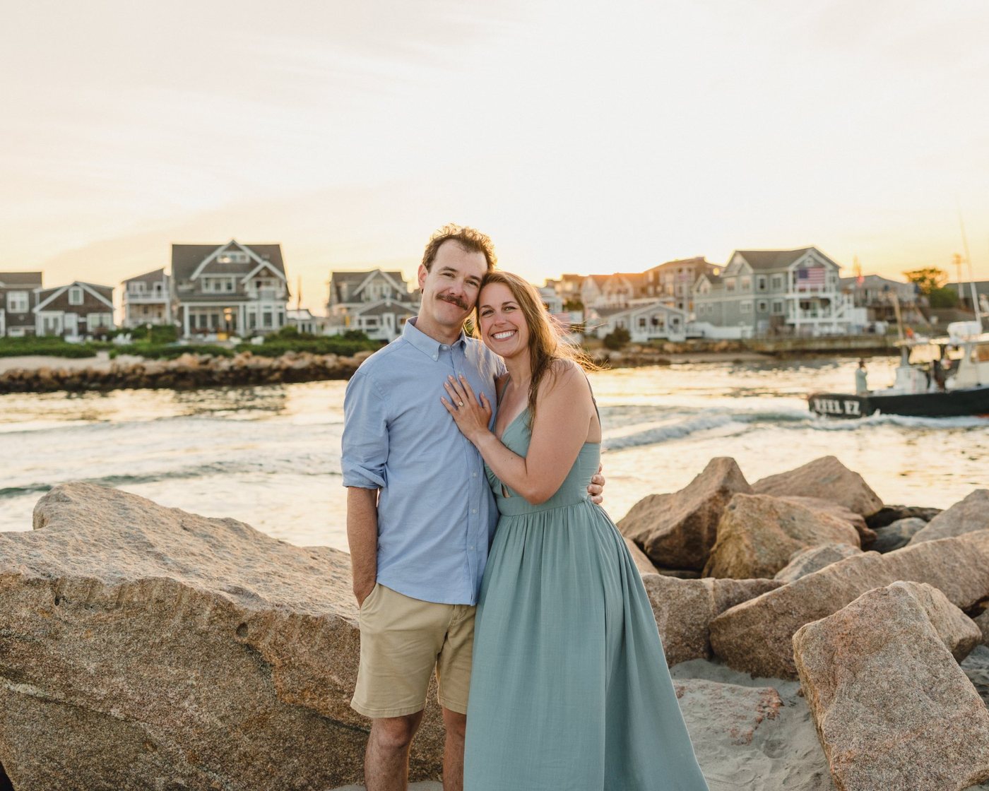 Sarah and Miles on the rocks by the water at sunset
